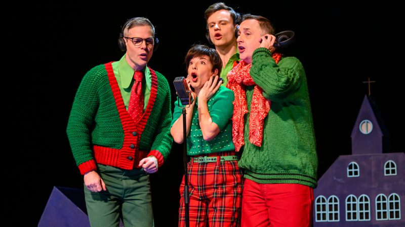 een groepje van drie mannen en een vrouw zingend in een microfoon in rood groene kerst kleding